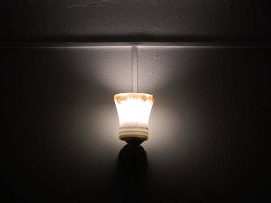 A single wall light illuminates a dark room.
